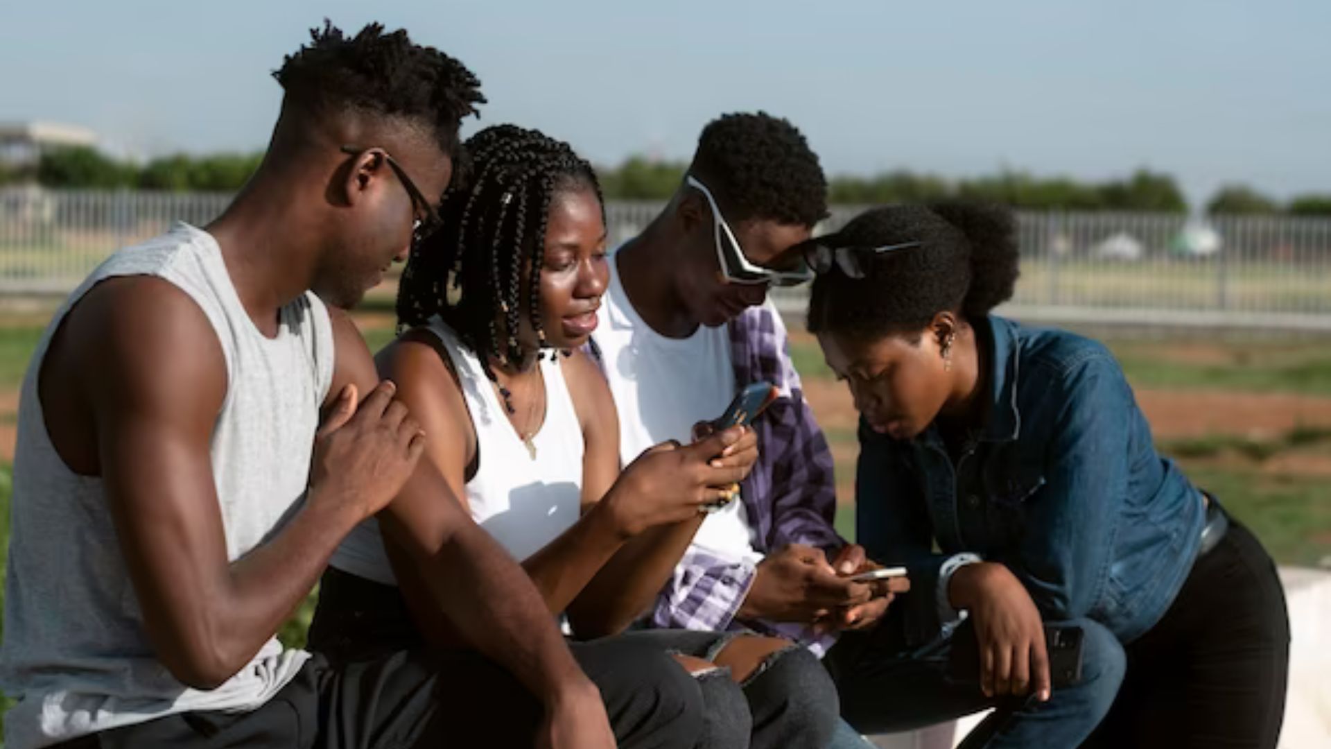 four young people playing games on their phones showing youth popular games 